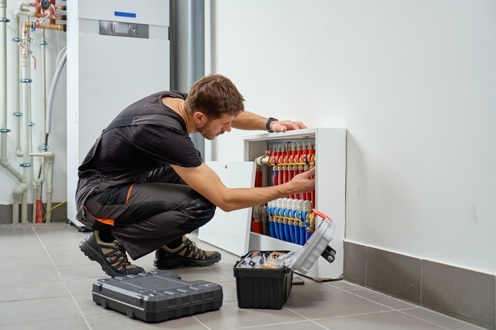 Installateur montiert einen Heizkreisverteiler